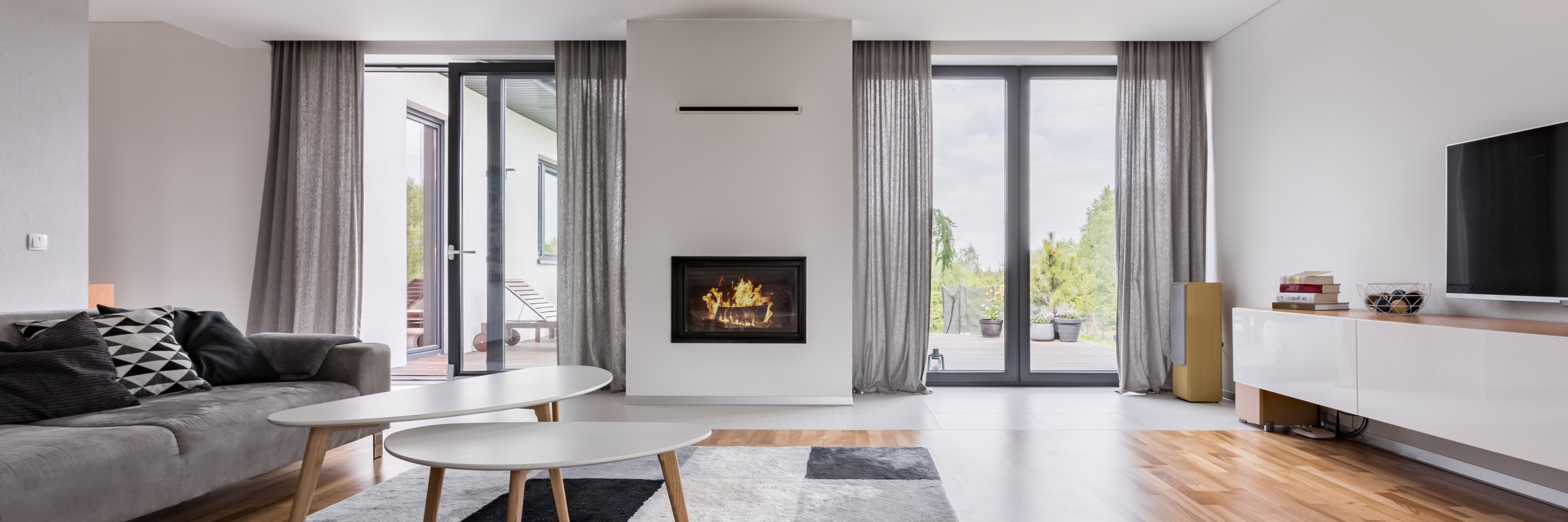 Grey sheer curtains in modern home with fireplace and large windows