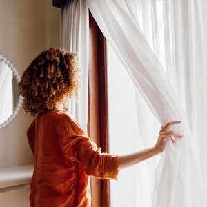 white sheer curtains with lady looking out window