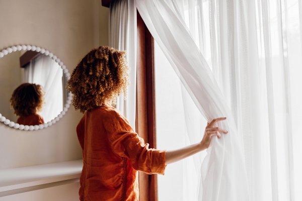 white sheer curtains with lady looking out window